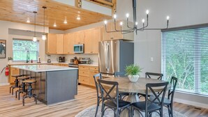 Une cuisine moderne avec des meubles en bois, un réfrigérateur en acier inoxydable et un îlot central doté de tabourets.