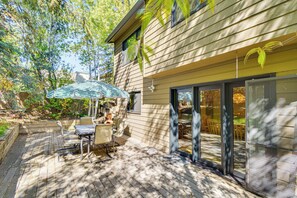 A patio with a table and chairs, a striped umbrella, and a sliding glass door leading to an interior space. - Large Family Duplex w/ Grill, Near Beaver Creek (Avon)