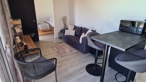 Una sala de estar moderna con un sofá, una mesa de comedor y una zona de cocina con microondas.