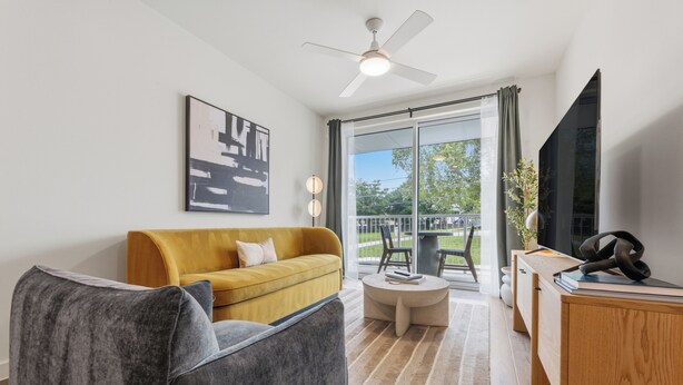 Een moderne woonkamer met een bank, fauteuil, salontafel en een tv op een houten kast.