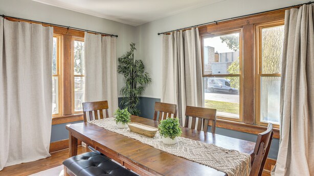 Un coin repas comprenant une table en bois, quatre chaises, un banc et une plante servant de décoration centrale.