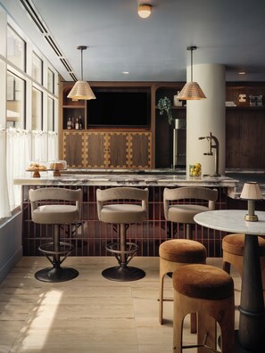 A modern kitchen with a bar area, wooden cabinets, and bar stools. - South Lamar Stay + Pool, Terrace | Accessible Queen Studio | The Code (Austin)