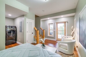 Een moderne slaapkamer met een groot bed, een wasmachine, een trap en uitzicht op de omgeving.