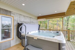 Een hottub op een houten terras met uitzicht op bomen.