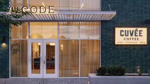 A modern building with a glass facade, a sign reading 'CUVÉE COFFEE,' and a balcony. - Near Zilker + Lady Bird | Pool + Bar | Accessible Queen Studio at The Code (Austin)