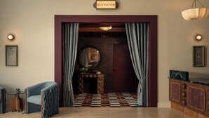 A room with a checkered floor, a fireplace, a mirror, and a sign indicating an elevator. - Near Zilker + Lady Bird | Pool + Bar | Accessible Queen Studio at The Code (Austin)