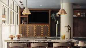 A modern kitchen with a bar area, wooden cabinets, and bar stools. - Near Zilker + Lady Bird | Pool + Bar | Accessible Queen Studio at The Code (Austin)