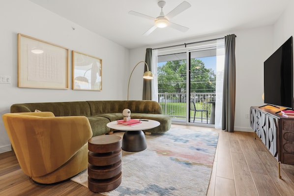 Un salon comprenant un canapé, un fauteuil, une table basse et un téléviseur à écran plat posé sur un meuble.