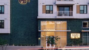 Un bâtiment moderne, avec un logo bien visible sur la façade, une entrée au niveau du sol et des balcons aux étages supérieurs.