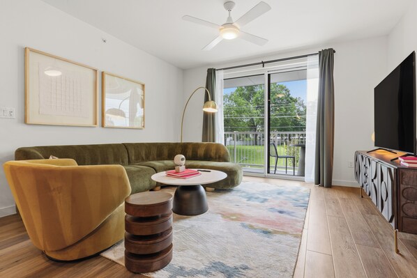 A living room with a sofa, armchair, coffee table, and a flat-screen TV.