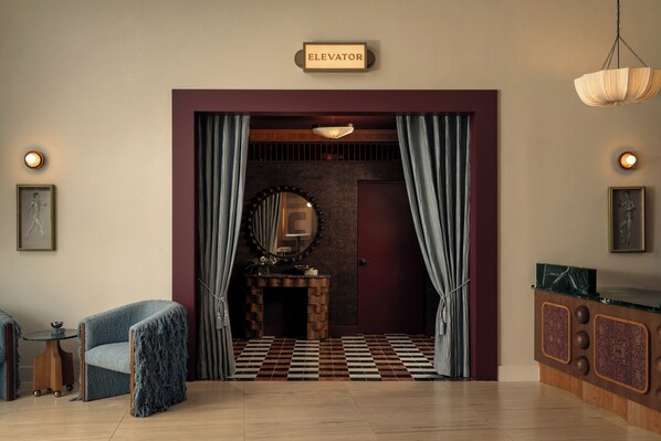 A room with a checkered floor, a fireplace, a mirror, and a sign indicating an elevator. - Experience Zilker & South Lamar from The Code | Private Balcony w/ Pool, Bar (Austin)