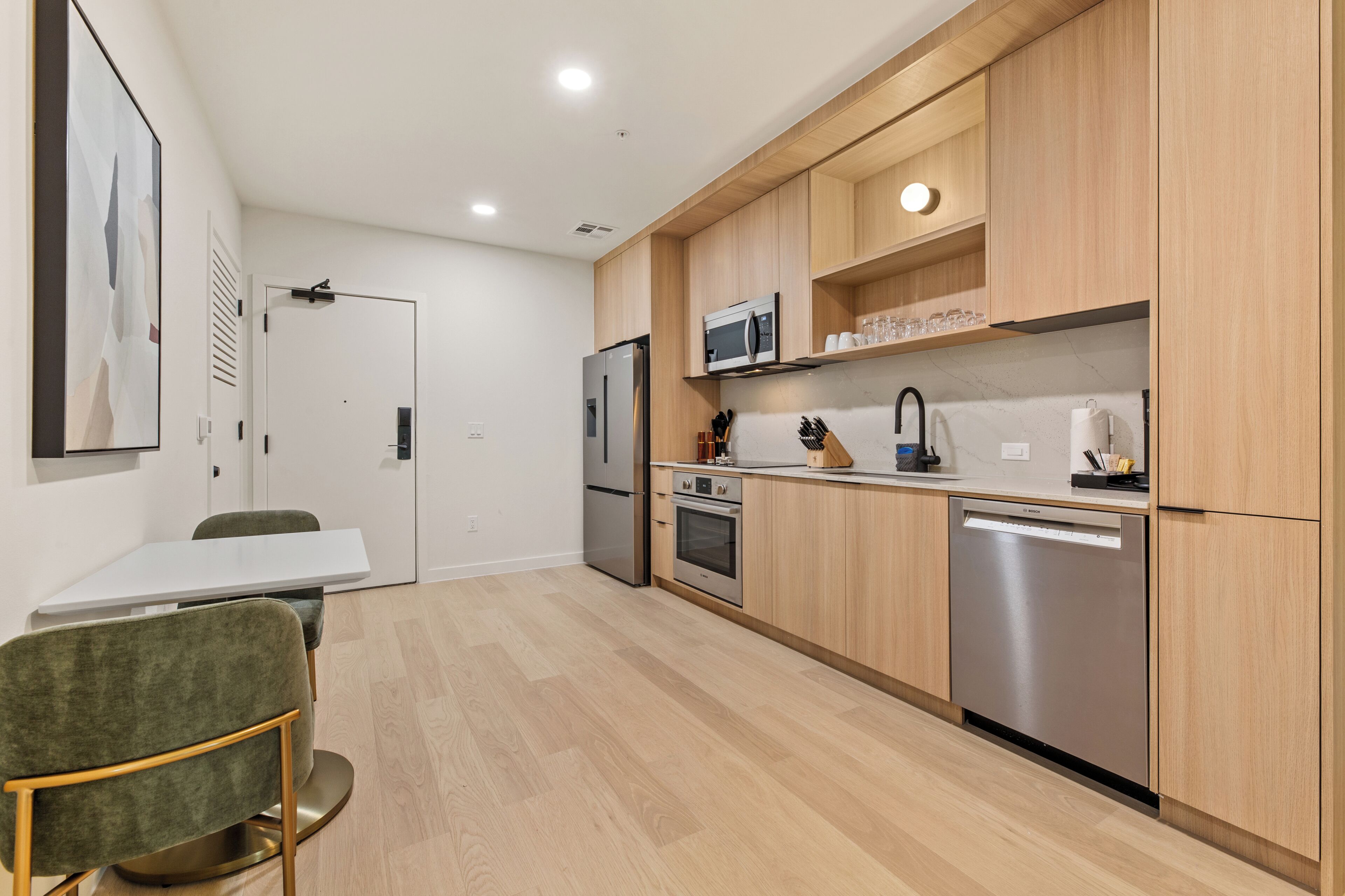 Een moderne keuken met houten kastjes, roestvrijstalen apparatuur en een witte eethoek.