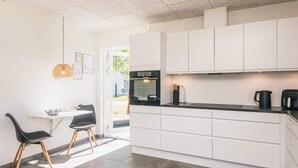 A modern kitchen with white cabinets, a black countertop, and a dining area with two chairs.