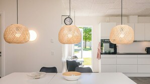 A modern kitchen with white cabinets, a black countertop, and a dining area with a white table and black chairs.
