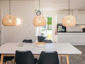 A modern kitchen with white cabinets, a black countertop, and a dining area with a white table and black chairs.
