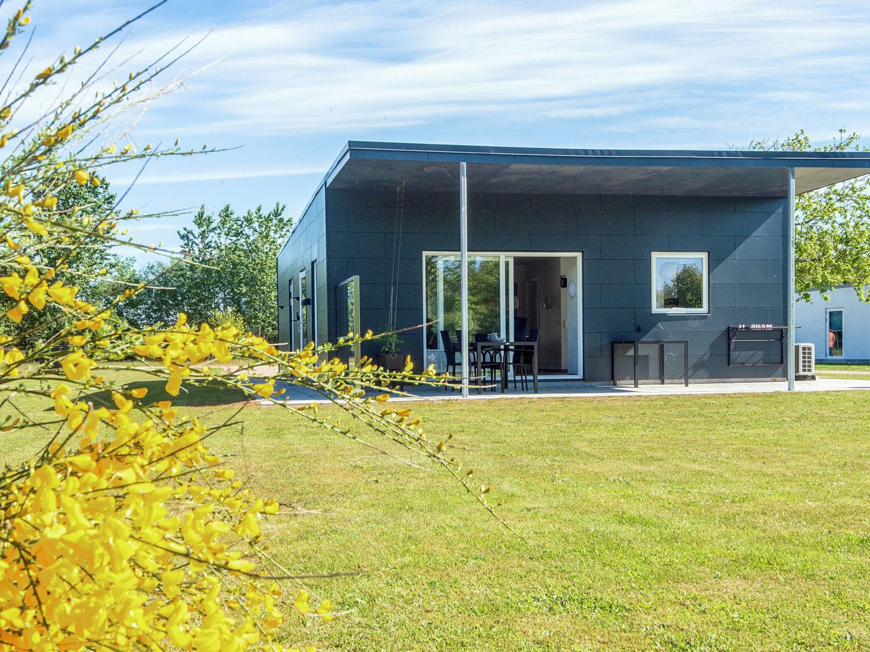A modern building with a flat roof, large windows, and a covered outdoor seating area.