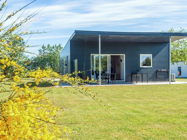 A modern building with a flat roof, large windows, and a covered outdoor seating area.
