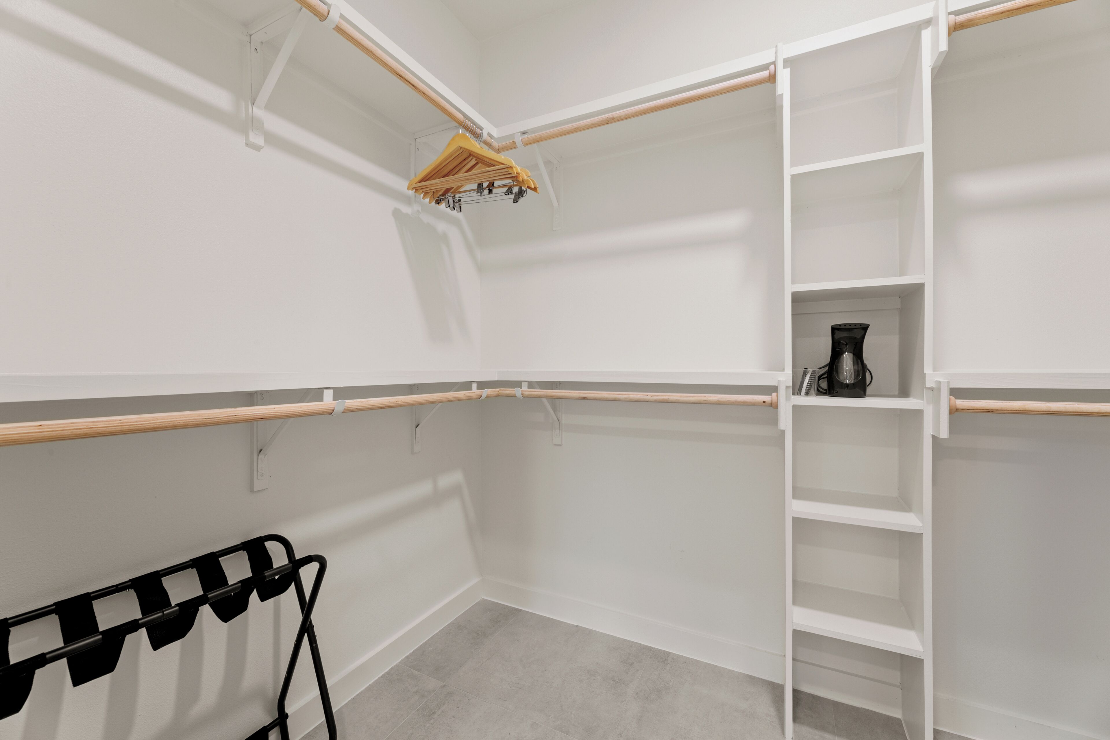Un dressing ouvert avec des étagères, une tringle et un porte-chaussures.