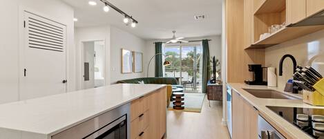A modern kitchen with a central island, built-in appliances, and a view to the outside.