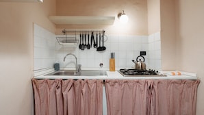 Une cuisine équipée d’un évier, d’une cuisinière et d’ustensiles de cuisine suspendus.