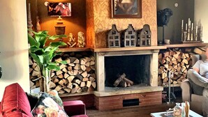 A cozy living room with a fireplace, a painting on the wall, and a red sofa.