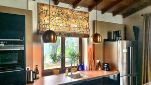 A modern kitchen with a built-in oven, stainless steel refrigerator, and pendant lights.