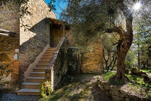 A stone staircase leading to a wooden door, surrounded by trees and a stone wall.