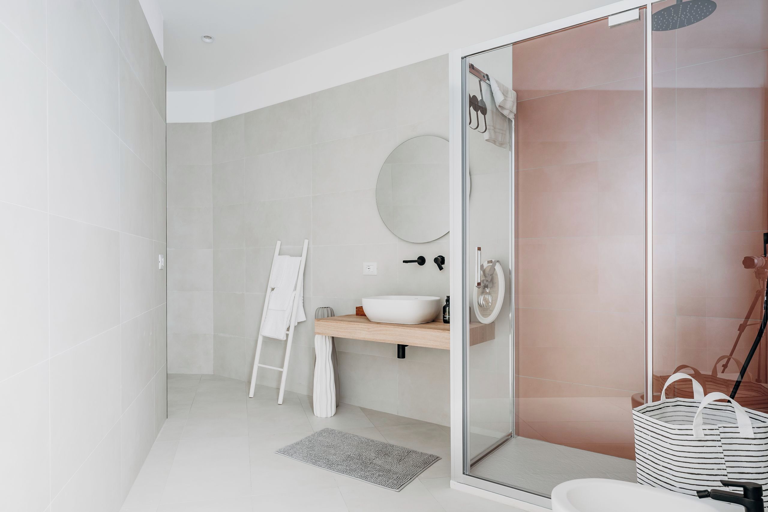 A modern bathroom with a glass shower enclosure, a white sink, and a wooden vanity.
