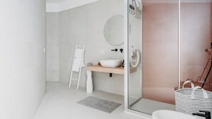 Ein modernes Badezimmer mit Duschkabine aus Glas, einem weißen Waschbecken und einem Holz-Badmöbelkorpus.