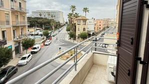Ein Balkon mit Blick auf eine Stadtstraße, Gebäude und Palmen.