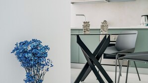 Eine moderne Küche mit einem Glastisch und schwarzen Stühlen, dazu eine Vase mit blauen Blumen auf der linken Seite.