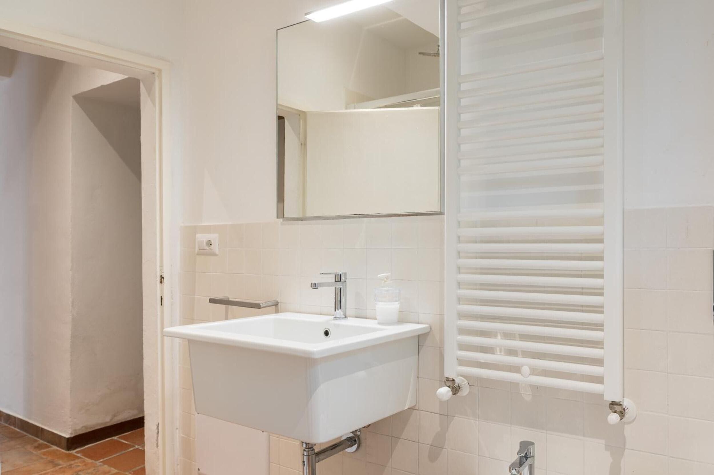 A bathroom with a white sink, mirror, and towel rack.