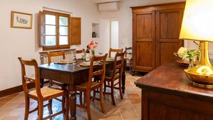 A dining area with a wooden table, chairs, a lamp, and a vase with flowers. - Apartment 'La Banditina' with Private Terrace, Wi-Fi and Air Conditioning (Vico dʼArbia)