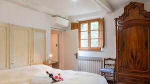 A bedroom with a bed, a wooden wardrobe, a radiator, and a window with a view of greenery. - Apartment 'La Banditina' with Private Terrace, Wi-Fi and Air Conditioning (Vico dʼArbia)