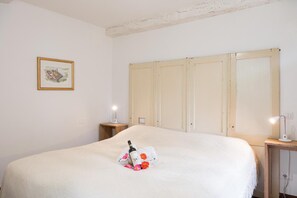 Un dormitorio con una cama grande, una mesita de noche con lámpara, un cuadro enmarcado en la pared y un armario con puertas correderas.