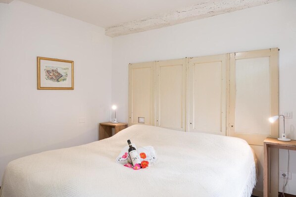 Une chambre avec un grand lit, une table de chevet avec une lampe, un tableau encadré au mur et une armoire avec des portes coulissantes.