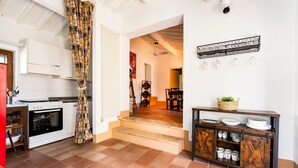 A kitchen with a stove, oven, and a dining area with a table and chairs. - Apartment 'Tiziana' with Shared Garden and Wi-Fi (Vico dʼArbia)