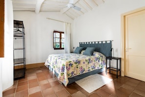A bedroom with a bed, a window, a ceiling fan, and a door.