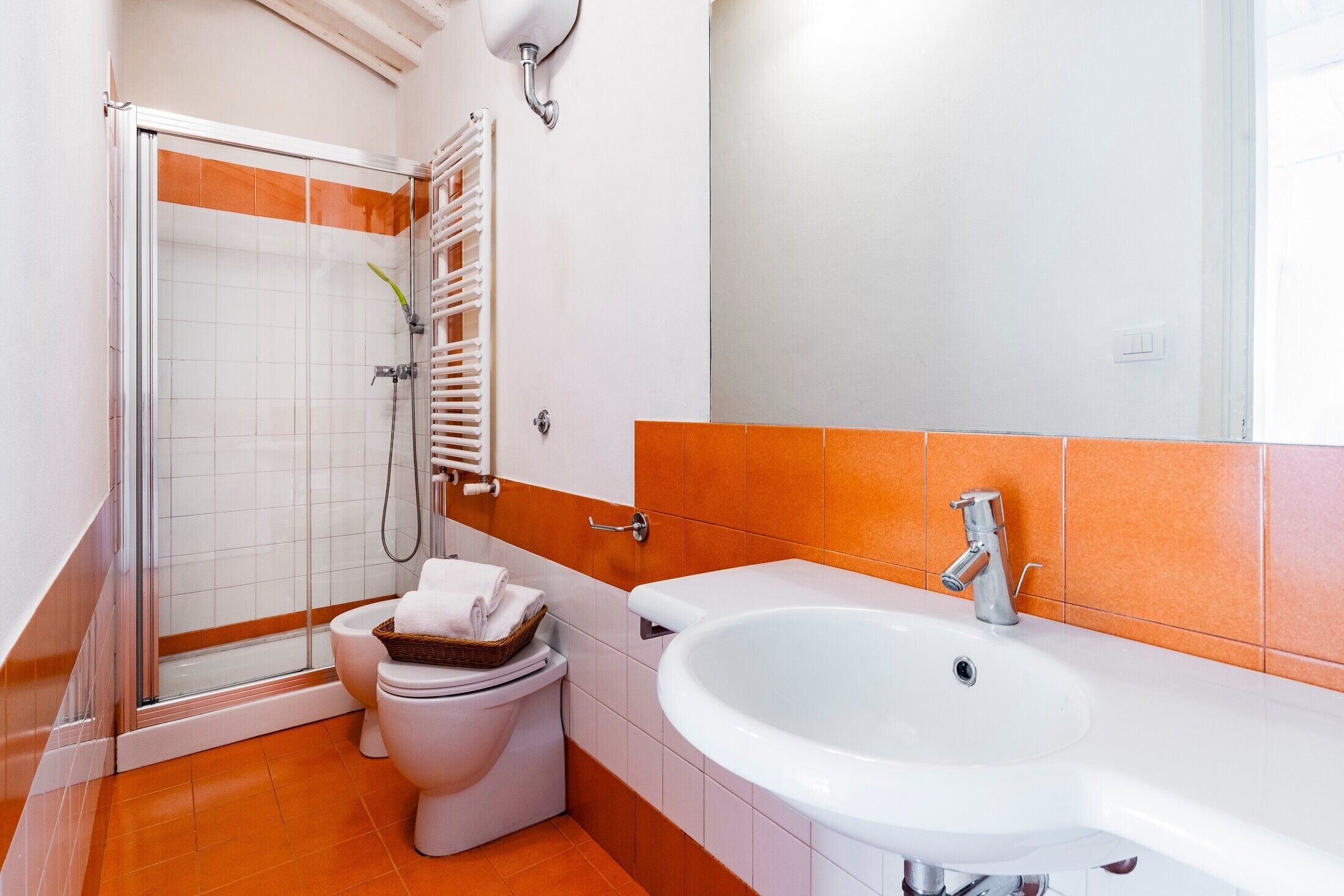 Un bagno con doccia, WC, lavandino e porta asciugamani.
