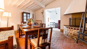 A dining area with a wooden table, chairs, and a fireplace. - Apartment 'Tiziana' with Shared Garden and Wi-Fi (Vico dʼArbia)