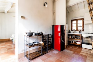 A kitchen with a red refrigerator, a stove, and various cooking utensils on shelves.
