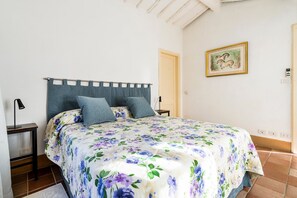 A bedroom with a bed, a nightstand, a wall-mounted picture, and a door.