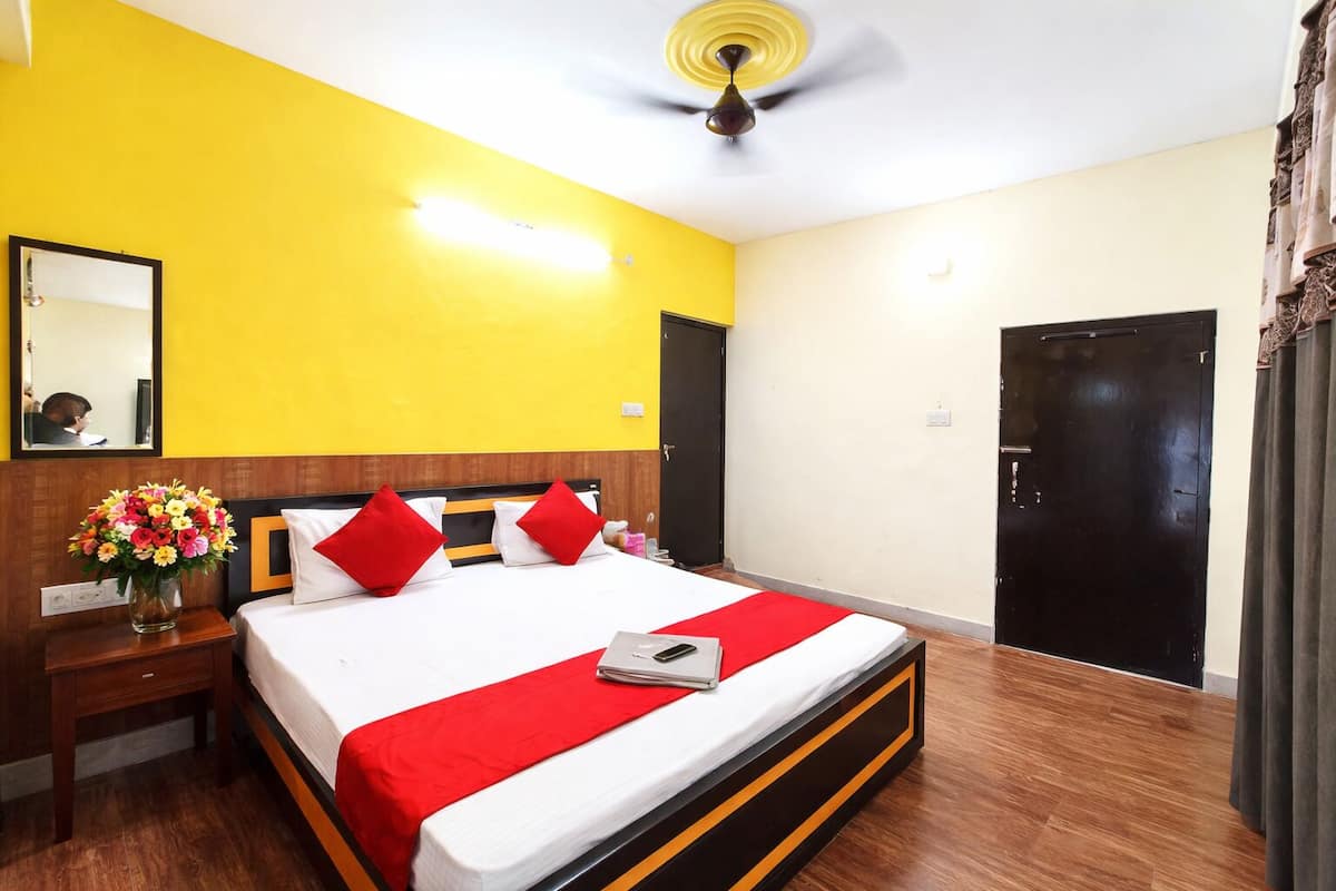 A hotel room with a bed, a nightstand, a mirror, a ceiling fan, and a door.