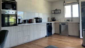 Een moderne keuken met inbouwapparatuur, een vaatwasser en een raam dat voor natuurlijk licht zorgt.