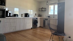 Een moderne keuken met een ingebouwde wasmachine en droger, een koffiezetapparaat en een hanglamp.