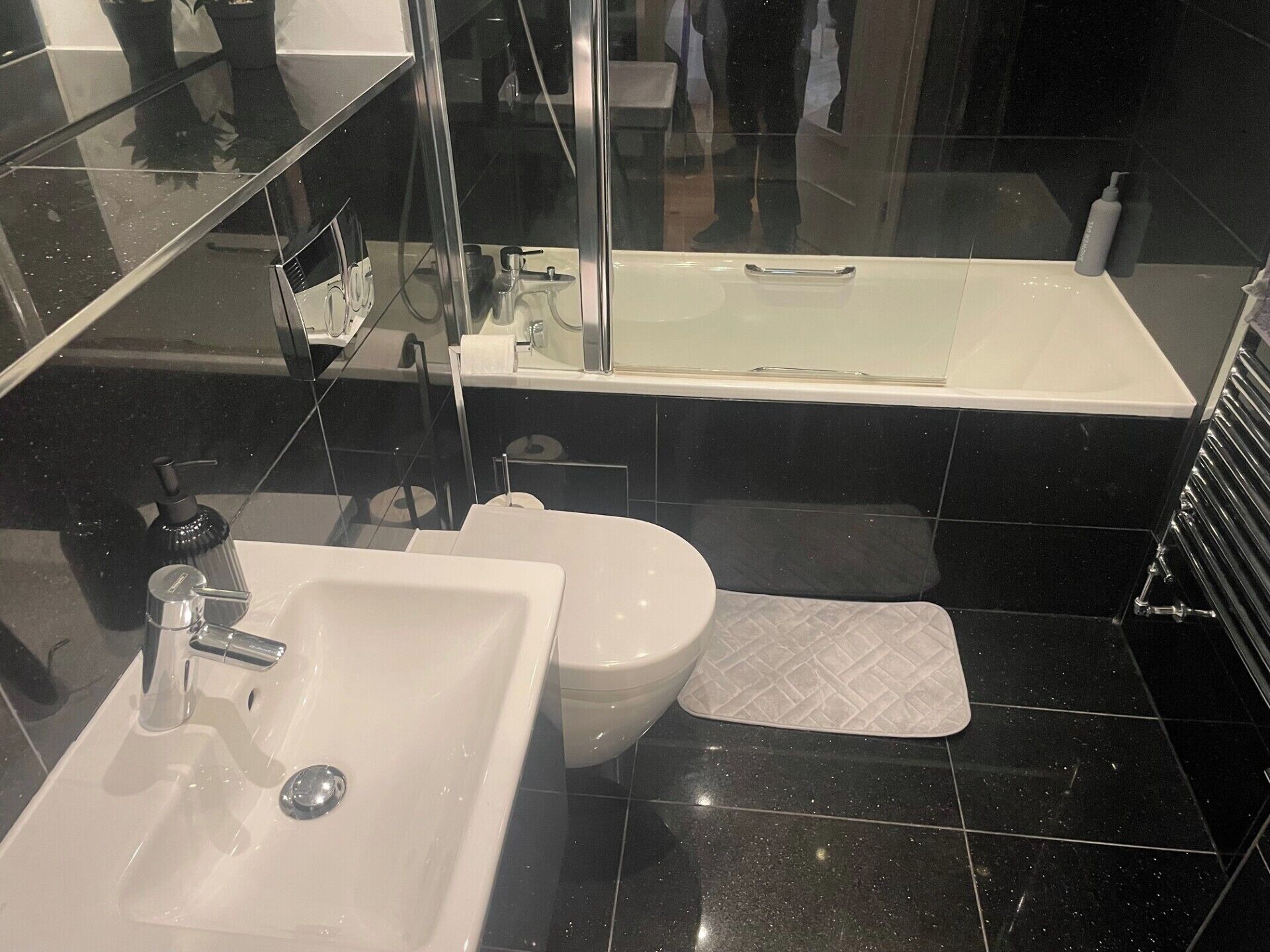 A modern bathroom with a white sink, a toilet, and a bathtub.