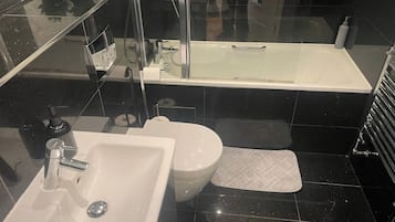 A modern bathroom with a white sink, a toilet, and a bathtub.