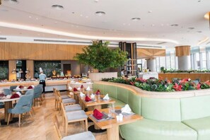 A modern restaurant interior with a curved seating area, a bar, and a large indoor plant. - Alacarte Halong Bay (Ha Long)