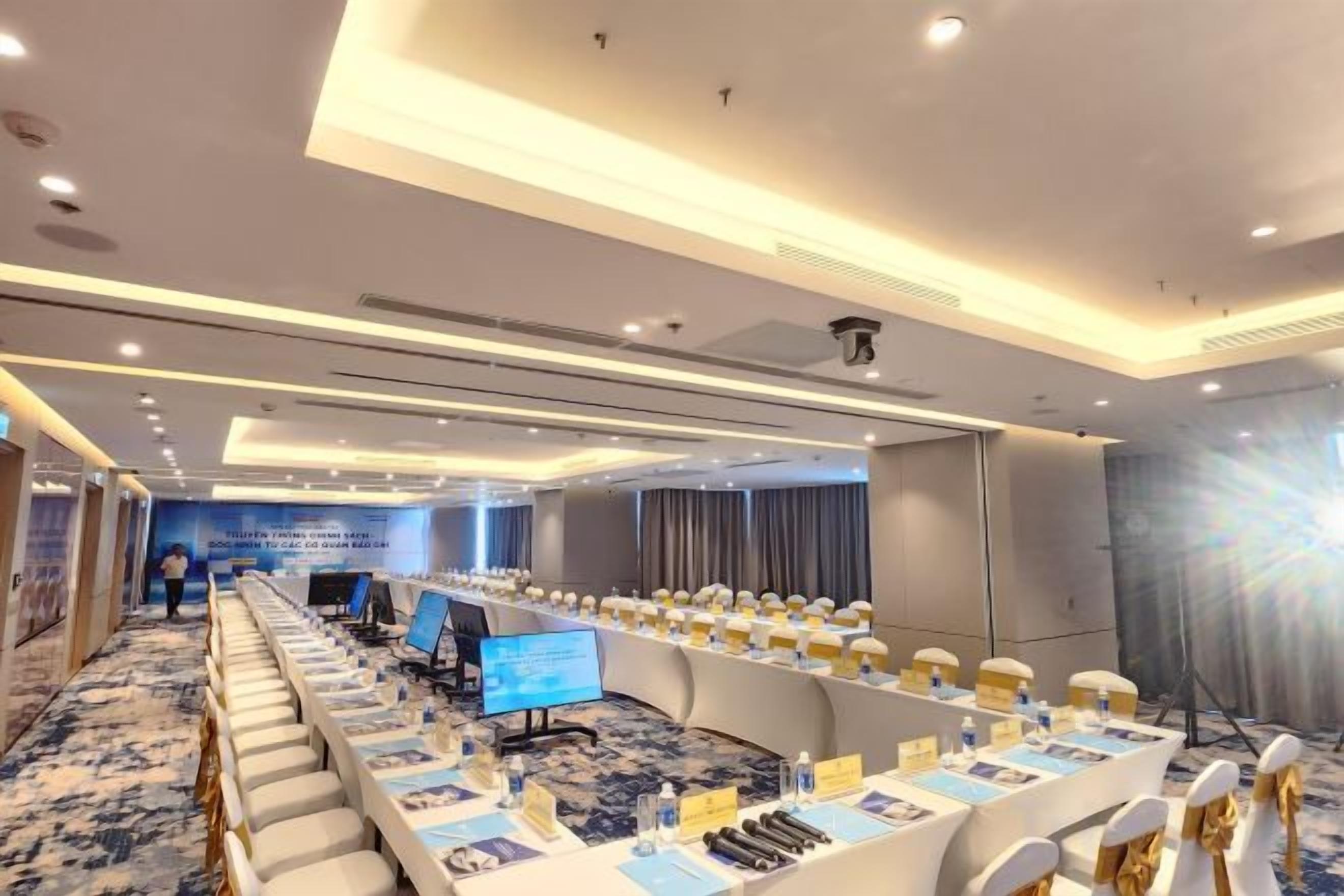 A conference room with a long table, chairs, and a presentation screen.