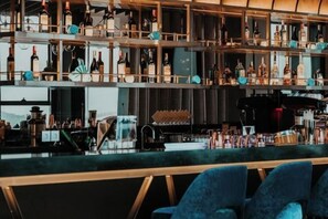 A bar area with shelves of bottles and a bar counter. - Alacarte Halong Bay (Ha Long)